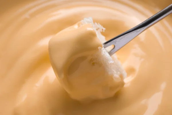 Dipping bread into tasty cheese fondue, closeup — Stock Photo, Image