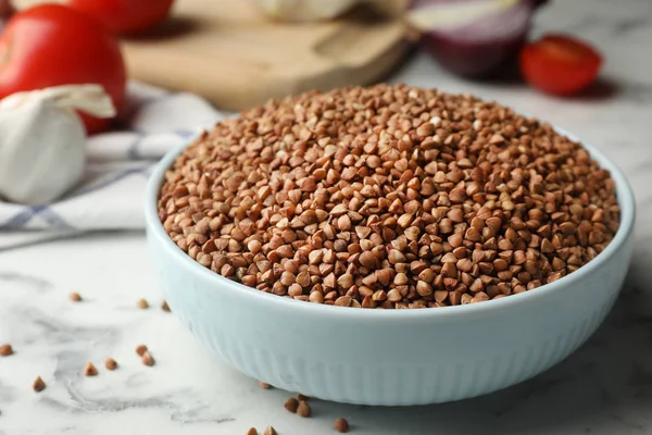 Bowl of uncooked buckwheat on marble table, closeup. Space for text — Stock Photo, Image