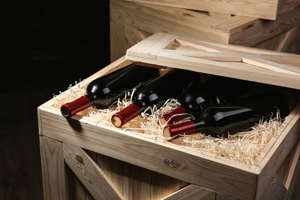 Caja de madera con botellas de vino sobre fondo oscuro, primer plano —  Fotos de Stock