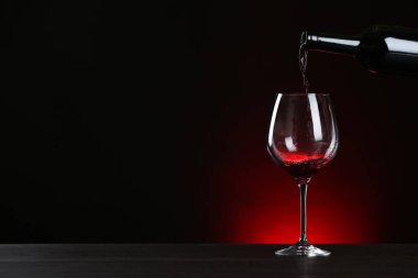 Koyu arka plana karşı masaya cam içine şişe şarap dökme, metin için alan