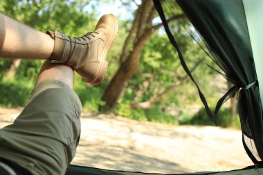 Ormanın yakınındaki kamp çadırında dinlenen genç adam, içeriden görünümü