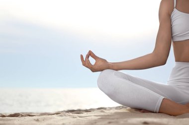 Genç kadın sahilde zen meditasyon uyguluyor, yakın çekim. Metin için alan
