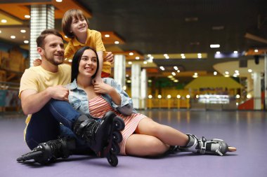 Happy family spending time at roller skating rink clipart