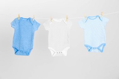 Açık gri arka plan karşı giysi hattı üzerinde asılı farklı bebek onesies. Çamaşır günü