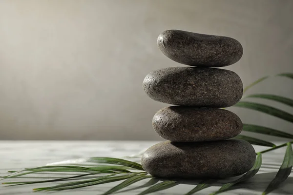 Stack van Spa stenen en Palm blad op grijze tafel, ruimte voor tekst — Stockfoto