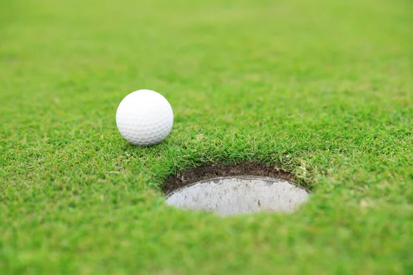 Boule de golf près du trou sur le parcours vert — Photo