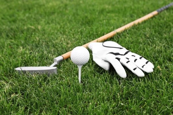 Гольф клуб з м'ячем, трійником і рукавичкою на зеленій траві — стокове фото