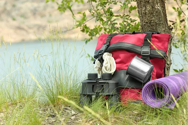 Rucksack und Campingausrüstung auf Gras in der Nähe von Bäumen in der Wildnis. Raum für Text — Stockfoto