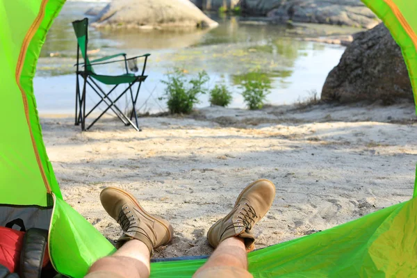 Young man resting in camping tent on riverbank, view from inside — Stock Photo, Image