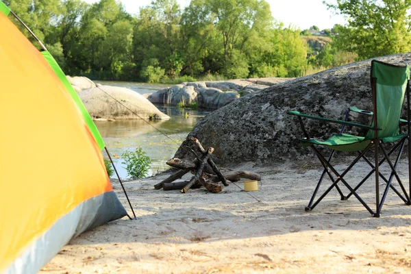 Nowoczesny namiot kempingowy z krzesłem i opałą na brzegu rzeki — Zdjęcie stockowe