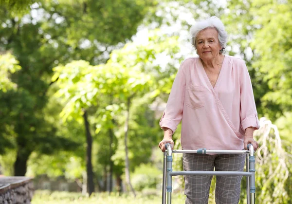 Ηλικιωμένη γυναίκα με το πλαίσιο πεζοπορίας σε εξωτερικούς χώρους. Ιατρική βοήθεια — Φωτογραφία Αρχείου