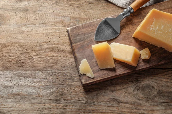 Junta con queso parmesano cortado sobre fondo de madera, vista superior. Espacio para texto — Foto de Stock