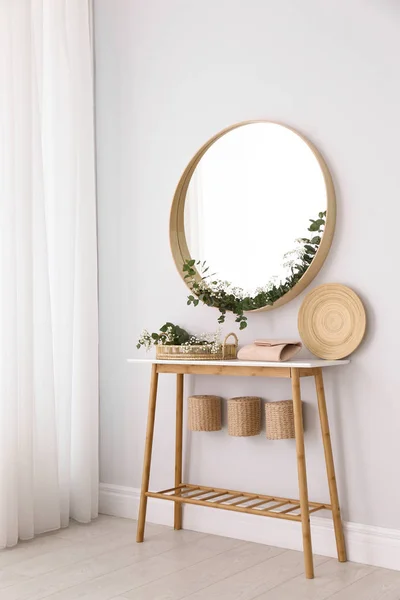 Miroir rond et table avec accessoires près du mur blanc. Design d'intérieur moderne — Photo