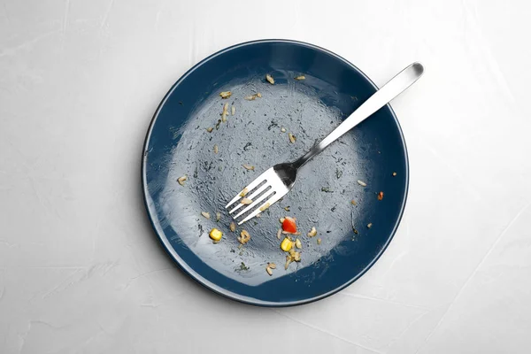 Piatto sporco con avanzi di cibo e forchetta su sfondo grigio, vista dall'alto — Foto Stock