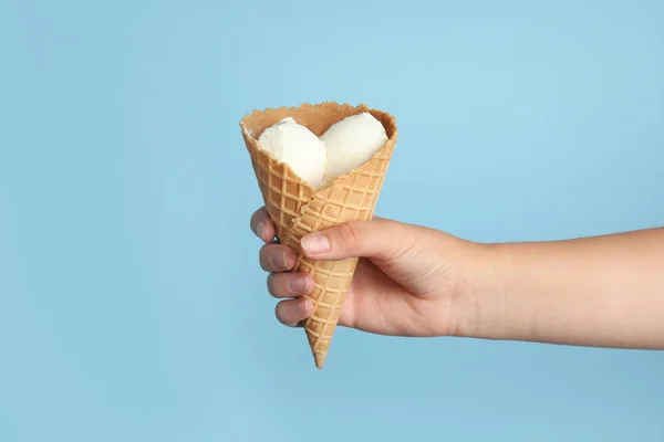 Mulher segurando delicioso sorvete em cone wafer no fundo azul, close-up — Fotografia de Stock