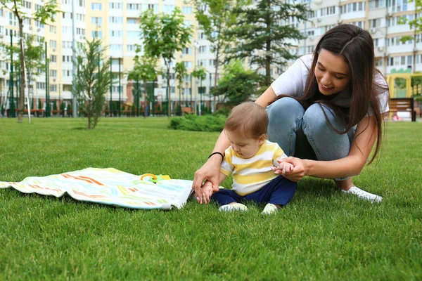 Giovane donna con adorabile bambino su erba verde all'aperto. Spazio per testo — Foto Stock