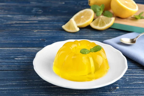 Plate with lemon jelly and mint on blue wooden table