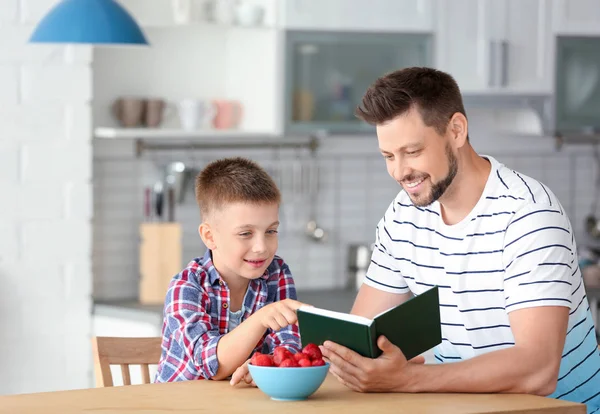 Vader en zoon lezen interessant boek in de keuken — Stockfoto