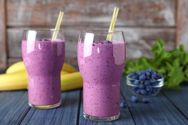 Mavi ahşap masa üzerinde lezzetli yaban mersini smoothie Gözlük