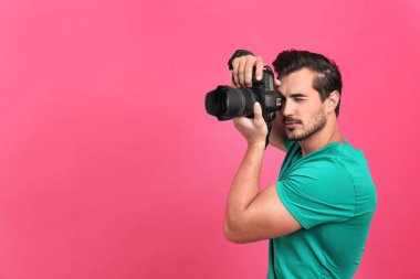 Genç profesyonel fotoğrafçı pembe arka planda fotoğraf çekiyor. Metin için alan