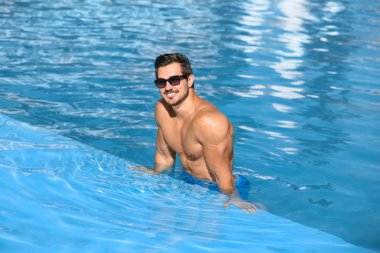 Güneşli bir günde yüzme havuzunda yakışıklı bir genç.