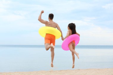 Mutlu genç çift denize yakın plajda şişme halkaları ile eğleniyor