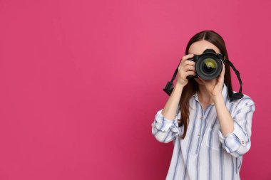 Profesyonel fotoğrafçı pembe arka planda fotoğraf çekiyor. Metin için alan