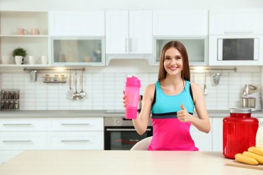 Mutfakta protein shake şişesi ile genç kadın