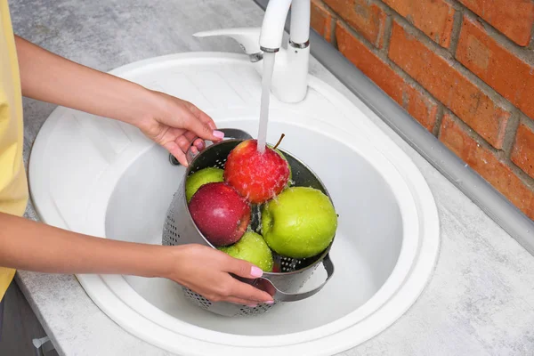 Женщина моет свежие яблоки в кухонной раковине, крупным планом — стоковое фото