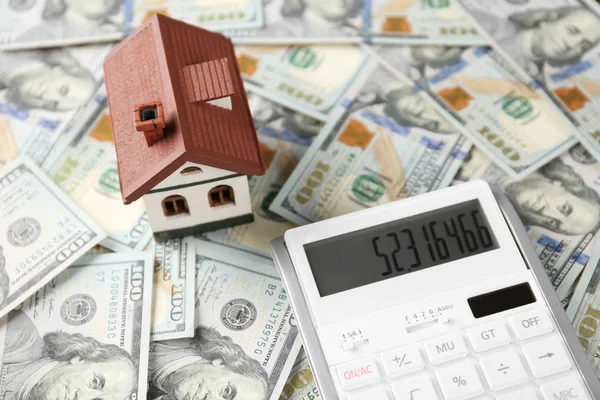 Calculator and house model on banknotes. Real estate agent concept — Stock Photo, Image