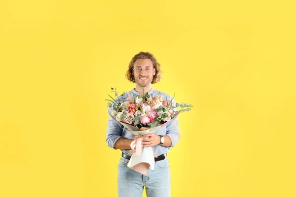 Jonge knappe man met mooie bloem boeket op gele achtergrond — Stockfoto