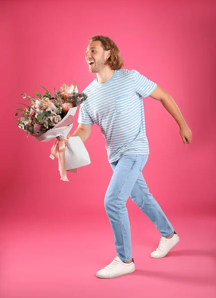 Pembe arka plan üzerinde güzel çiçek buketi ile genç yakışıklı adam — Stok fotoğraf
