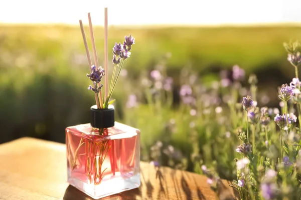 Reed penyegar udara dengan minyak dan bunga lavender segar di atas meja kayu di lapangan mekar. Ruang untuk teks — Stok Foto