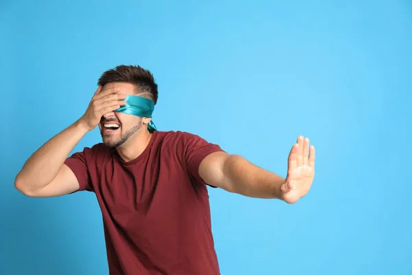Young man with blindfold on blue background — Stock Photo, Image