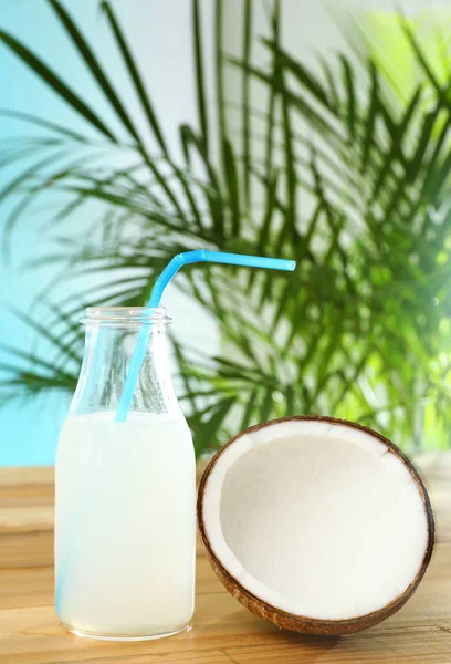 Samenstelling met fles kokoswater op houten tafel tegen blauwe achtergrond — Stockfoto