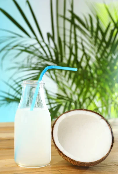 Composición con botella de agua de coco sobre mesa de madera sobre fondo azul — Foto de Stock