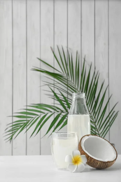 Composizione con bottiglia e bicchiere di acqua di cocco su tavolo di legno bianco — Foto Stock