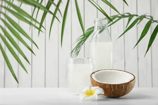 Složení s lahví a sklenicí kokosové vody na bílém dřevěném stole — Stock fotografie