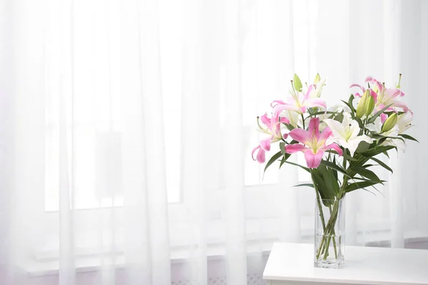 Vase with bouquet of beautiful lilies on white table indoors. Space for text — Stock Photo, Image