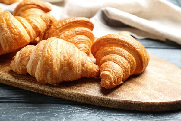 Board ízletes croissant a sötét fából készült asztal, closeup. Francia cukrászsütemény — Stock Fotó