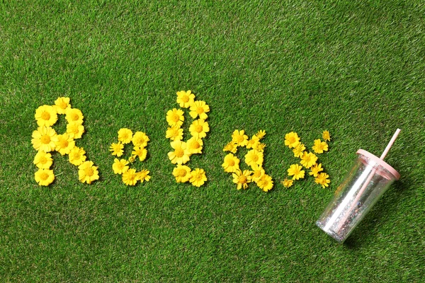 Слово RELAX желтых цветов с чашкой на зеленой траве, плоский лежал — стоковое фото
