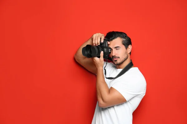 Jovem fotógrafo profissional tirando fotos em fundo vermelho. Espaço para texto — Fotografia de Stock