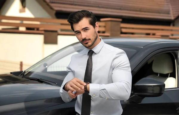 Aantrekkelijke jonge man controletijd in de buurt van luxe auto buitenshuis — Stockfoto