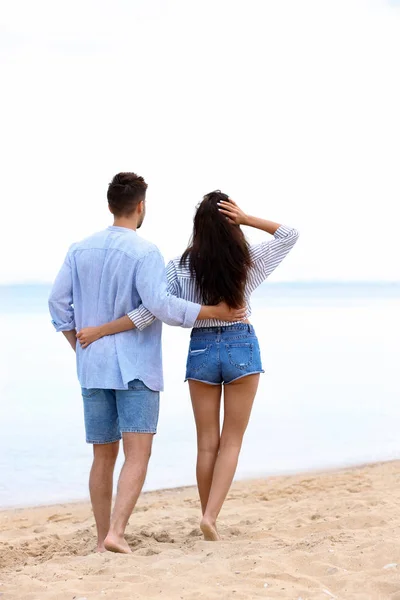 Glückliches junges Paar, das zusammen am Strand am Meer spaziert — Stockfoto