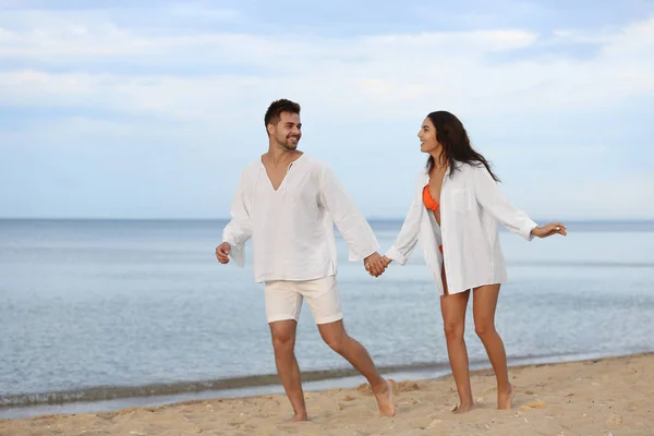Felice giovane coppia a piedi insieme sulla spiaggia vicino al mare — Foto Stock