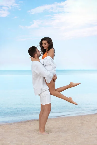 Feliz pareja joven pasar tiempo juntos en la playa cerca del mar — Foto de Stock