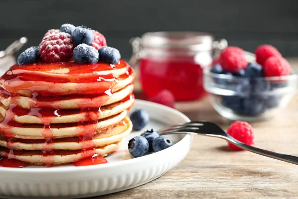 Pancake lezat dengan buah beri segar dan sirup di atas meja kayu, closeup — Stok Foto