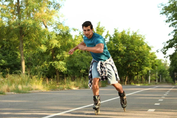 Handsome young man roller skating in park