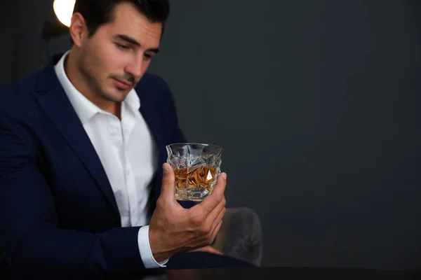 Jeune homme avec un verre de whisky sur fond sombre. Espace pour le texte — Photo