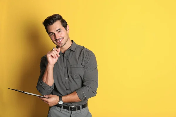 Joven profesor con portapapeles sobre fondo amarillo. Espacio para texto — Foto de Stock